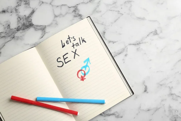 Notebook s frází "Mluvme o sexu" a symboly pohlaví na mramorovém pozadí, pohled shora — Stock fotografie