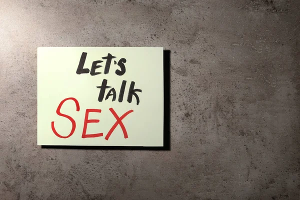 Uwaga z frazą "Let's talk sex" na tle kamienia, widok z góry — Zdjęcie stockowe