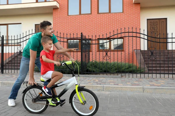 Père heureux enseignant à son fils à faire du vélo dans la rue — Photo