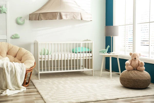 Cute nursery interior with comfortable crib near white wall — Stock Photo, Image