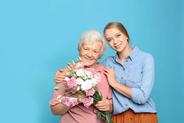 一个年轻的女人和她的祖母，花浅蓝色背景 — 图库照片