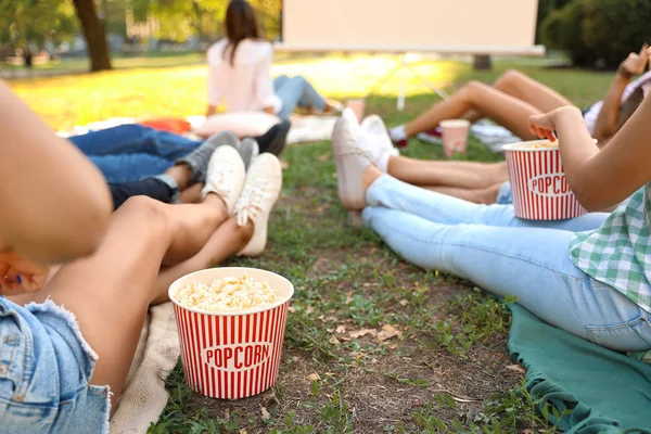 Młodzi ludzie z popcornem oglądają film w kinie na świeżym powietrzu, zbliżenie — Zdjęcie stockowe