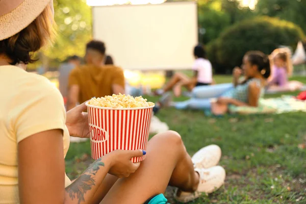 Young woman with popcorn watching movie in open air cinema, closeup. Space for text — Stock Photo, Image