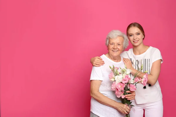一个年轻的女人和她的祖母带着粉色背景的花。 案文的篇幅 — 图库照片