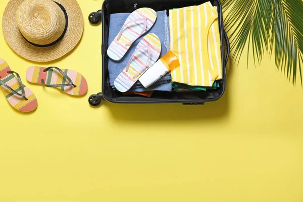 Відкрита валіза та пляжні аксесуари на жовтому тлі, плоска постіль. Простір для тексту — стокове фото