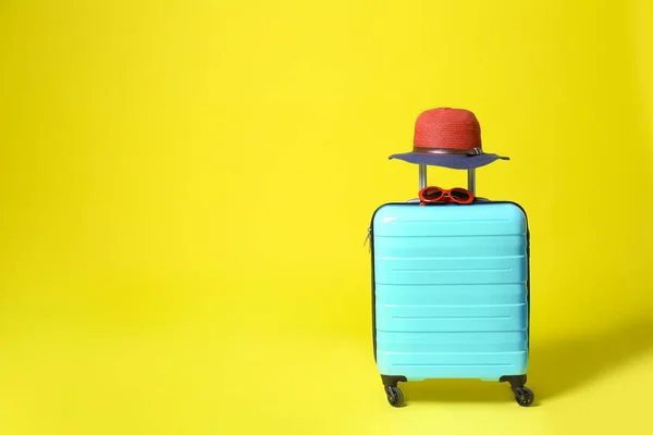 Elegante maleta azul con sombrero y gafas de sol sobre fondo amarillo. Espacio para texto — Foto de Stock