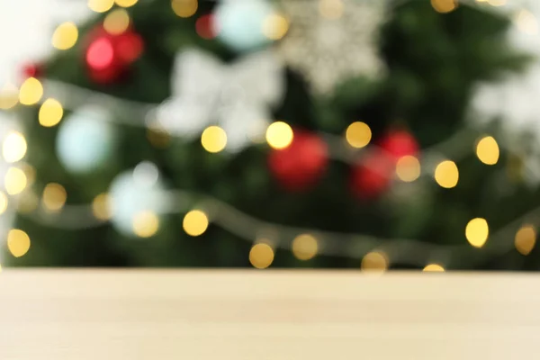 Порожній дерев'яний стіл проти ялинки з різдвяними вогнями, розмитим видом. Простір для дизайну — стокове фото