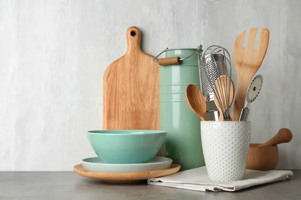 Diferentes utensilios de cocina sobre mesa gris sobre fondo claro — Foto de Stock