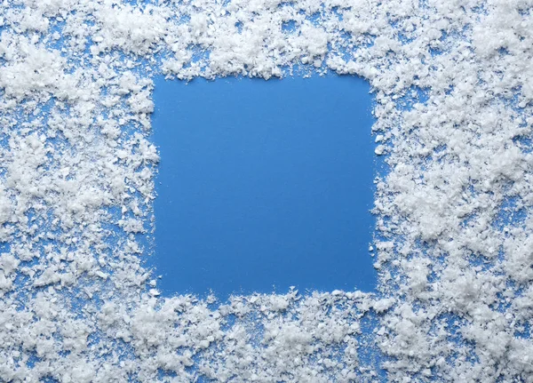 Frame gemaakt van sneeuw op blauwe achtergrond, bovenaanzicht met ruimte voor tekst. Winterseizoen — Stockfoto