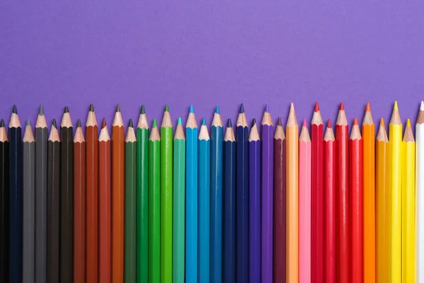 Crayons colorés sur fond violet, pose plate — Photo