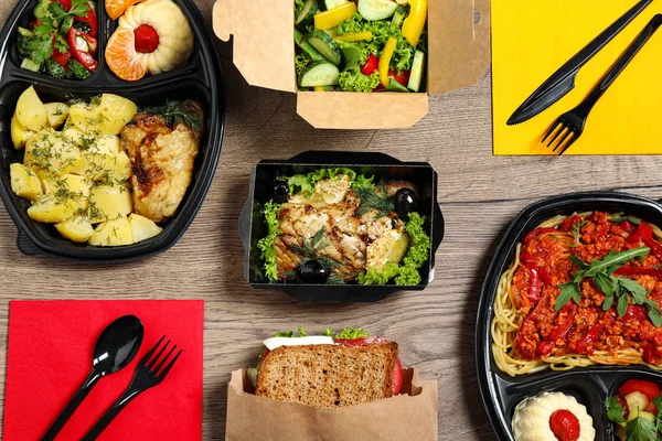 Lunchboxen met verschillende maaltijden op houten tafel, vlakke lag. Gezond eten bezorgen — Stockfoto
