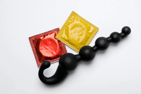 Анальные шарики и презервативы на белом фоне, вид сверху. Секс-игра — стоковое фото