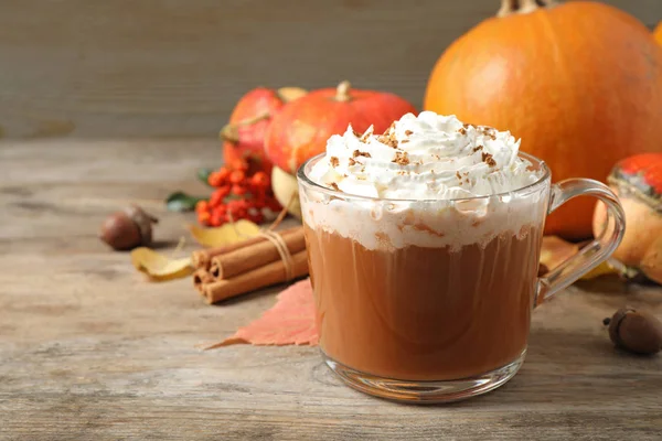 Copa de vidrio con sabroso café con leche de especias de calabaza en la mesa de madera, espacio para el texto — Foto de Stock