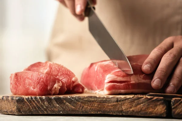 Man cutting fresh raw meat on wooden board, closeup Stock Image