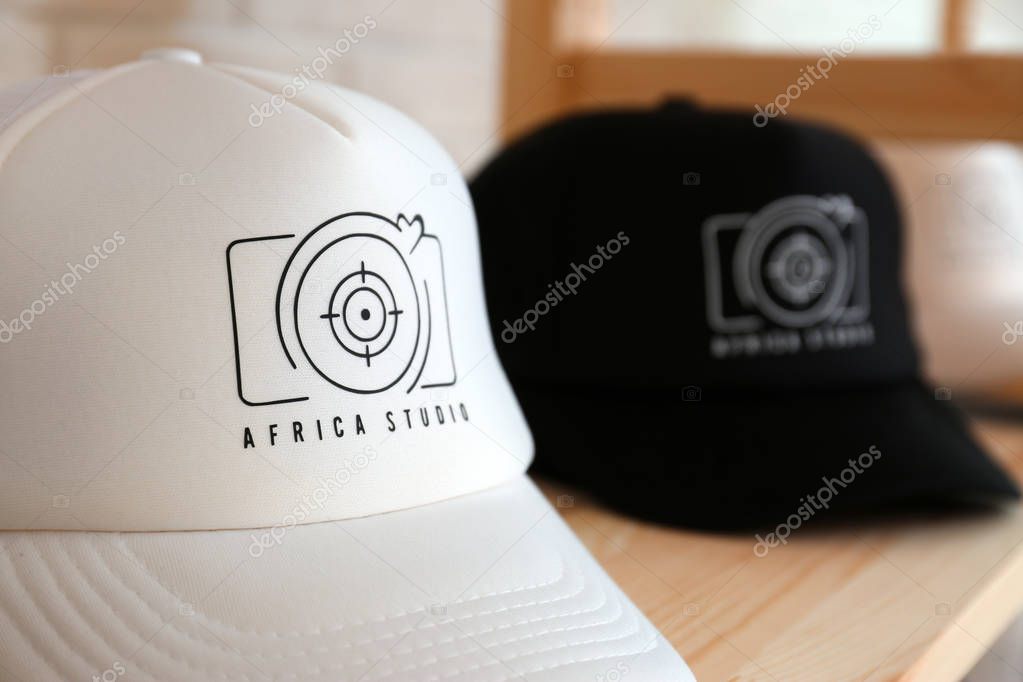 Caps with logo on wooden shelf in shop, closeup