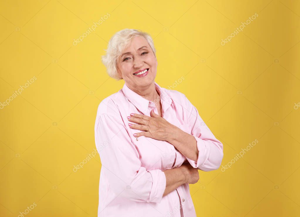 Emotional senior woman in casual outfit on yellow background