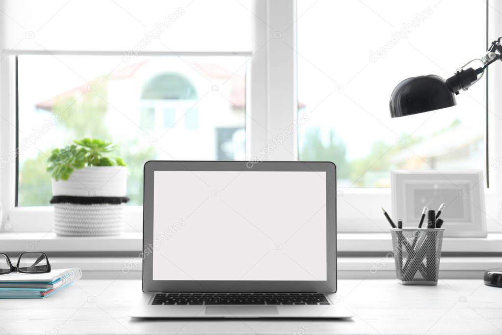Modern laptop on desk near window at home