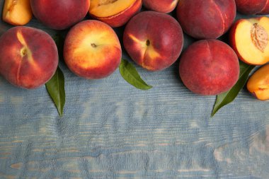 Taze şeftali ve yapraklar mavi ahşap masa üzerinde, üst görünümü metin için alan