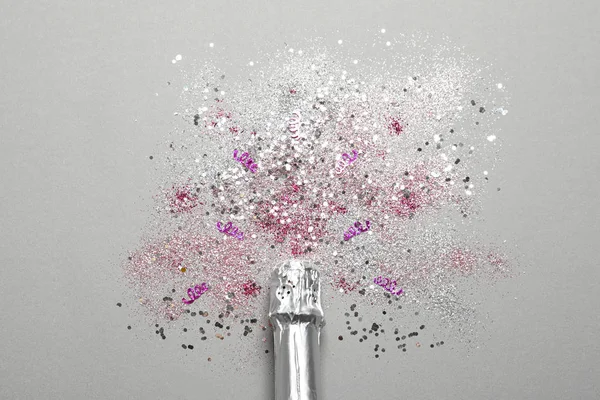 Μπουκαλάκι σαμπάνιας για γιορτή με glitter και κομφετί σε γκρι φόντο, top view — Φωτογραφία Αρχείου