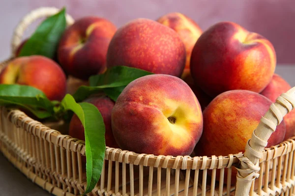 Wicker tray with juicy peaches on table, closeup