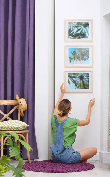 Vrouwelijke interieur ontwerper versieren witte muur met Foto's binnenshuis — Stockfoto