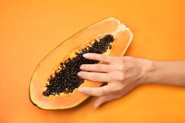 Genç bir kadın turuncu arka planda papaya 'nın yarısına dokunuyor. Seks konsepti