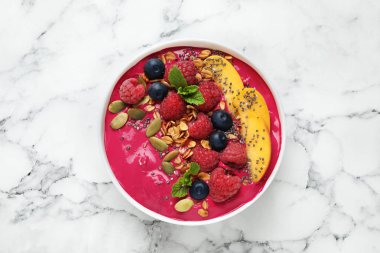 Tahıl gevreğiyle nefis acai smoothie ve beyaz mermer masa üzerindeki tatlı kasesinde böğürtlen, üst manzara