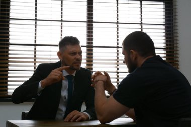 Kızgın dedektif sorgu odasında suçluyu sorguluyor.