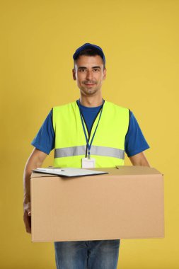 Sarı arka plan üzerinde karton kutu ve pano ile Mutlu genç kurye
