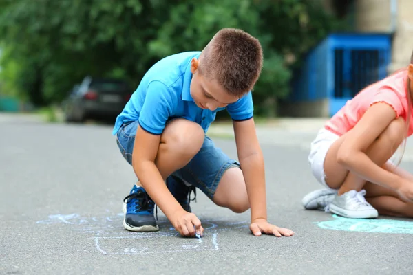 Kleines Kind zeichnet mit Kreide auf Asphalt. Spiel im Freien — Stockfoto