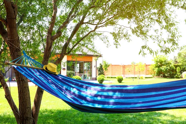 Güneşli bir günde açık havada şapkası ve kitabı olan rahat mavi bir hamak.