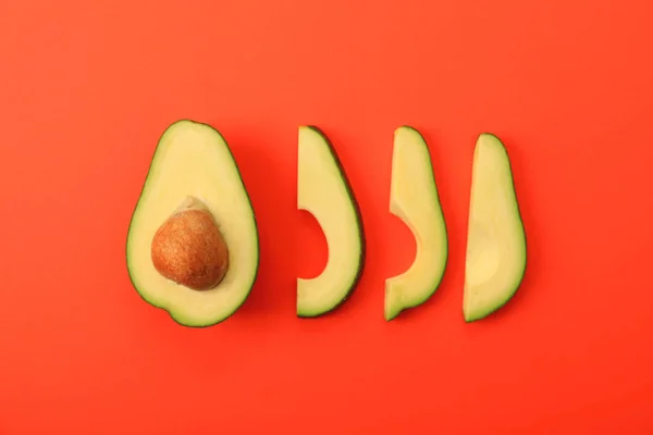 Platte lay compositie met avocado plakjes op rode achtergrond — Stockfoto