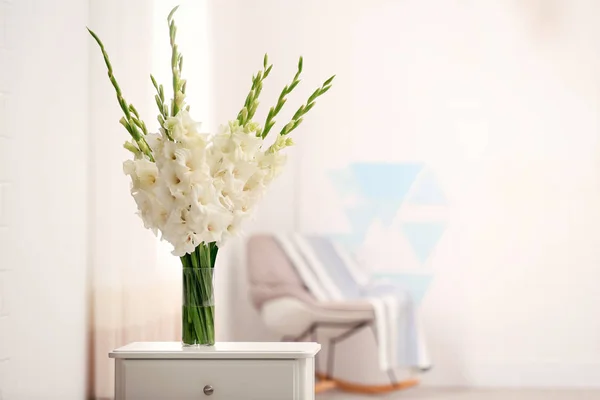 Vas dengan indah bunga gladiolus putih di laci dada di kamar, ruang untuk teks — Stok Foto