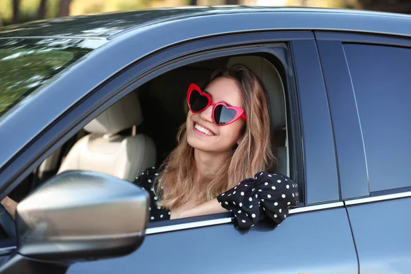 Jovem mulher bonita vestindo óculos em forma de coração no carro — Fotografia de Stock