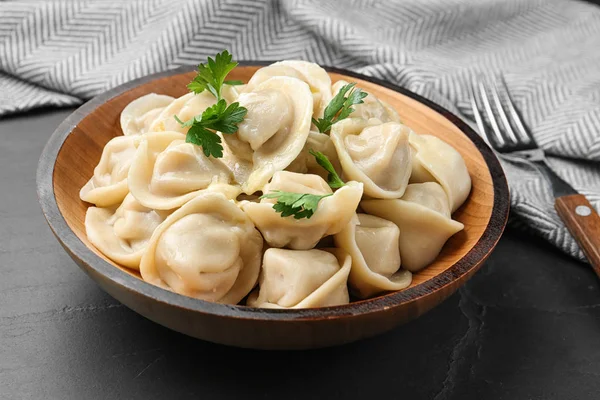 Smakliga dumplings med persilja i skål på svart bord — Stockfoto