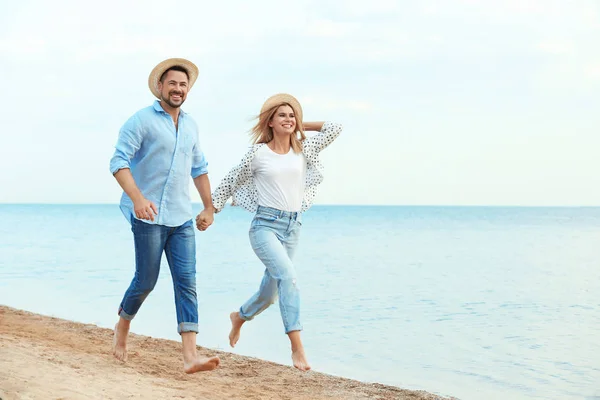 Feliz casal romântico correndo juntos na praia, espaço para texto — Fotografia de Stock