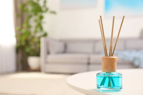 Reed air freshener with essential oil on table in room. Space for text