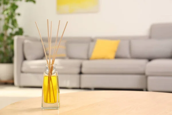 Reed air freshener with essential oil on table in room. Space for text