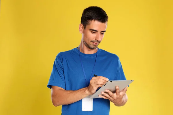 Feliz joven mensajero con la tableta sobre fondo amarillo — Foto de Stock