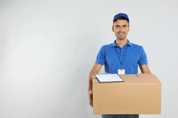 Correios jovens felizes com caixa de papelão e área de transferência em fundo branco. Espaço para texto — Fotografia de Stock