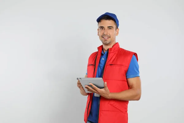 Glücklicher junger Kurier mit Tablet auf weißem Hintergrund — Stockfoto