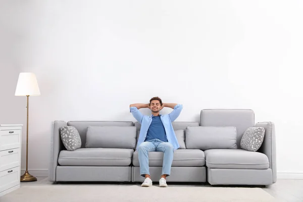 Jeune homme relaxant sur canapé à la maison — Photo