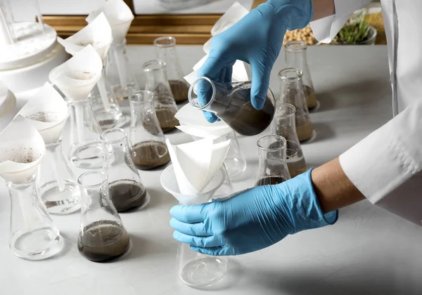 Wetenschapper filteren bodemmonsters aan tafel, close-up. Laboratoriumanalyse — Stockfoto