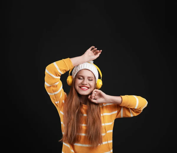 Молода жінка слухає музику з навушниками на чорному фоні — стокове фото