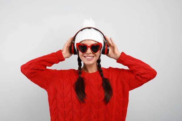 Jovem ouvindo música com fones de ouvido em fundo cinza — Fotografia de Stock