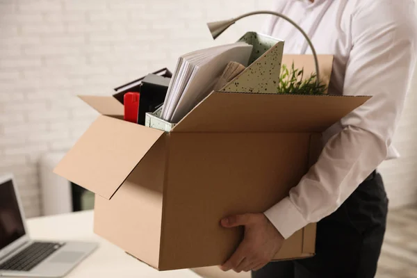 Молодой человек с коробкой вещей в офисе, крупным планом — стоковое фото