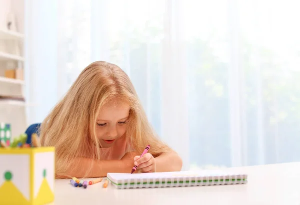 Nettes kleines Linkshändermädchen zeichnet am Tisch im Zimmer — Stockfoto