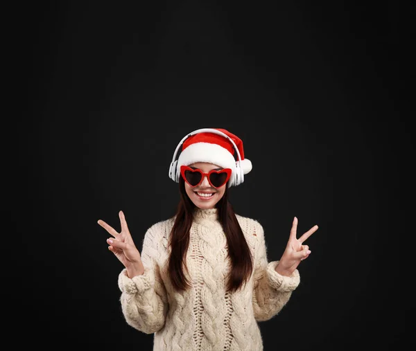 Jovem em Santa hat ouvindo música de Natal em fundo preto — Fotografia de Stock