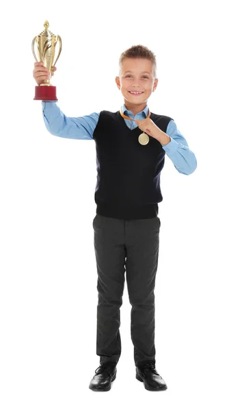 Szczęśliwy chłopiec w mundurze szkolnym ze złotym zwycięski Puchar i medal na białym tle — Zdjęcie stockowe