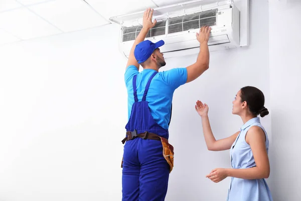 Técnico profissional falando com a mulher sobre ar condicionado dentro de casa — Fotografia de Stock